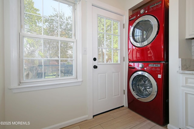 clothes washing area featuring stacked washing maching and dryer, light wood finished floors, and laundry area