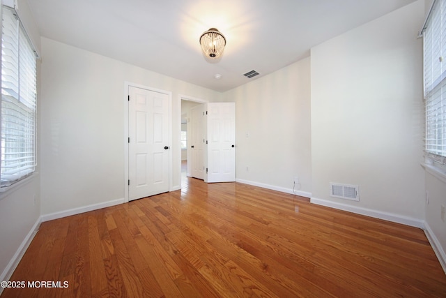 unfurnished bedroom with visible vents, wood finished floors, and baseboards