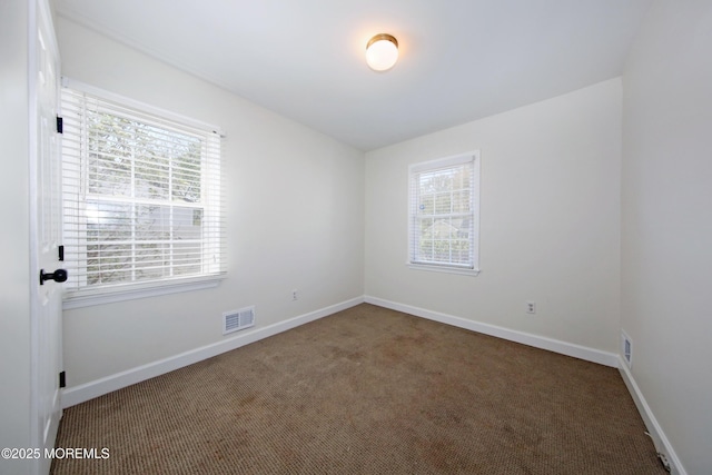 carpeted empty room with a wealth of natural light, visible vents, and baseboards