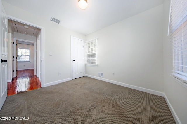 unfurnished bedroom featuring attic access, visible vents, baseboards, and carpet floors