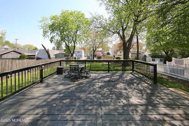 wooden terrace with fence, outdoor dining space, and a residential view