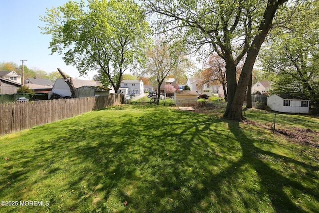 view of yard featuring fence, a residential view, and an outbuilding