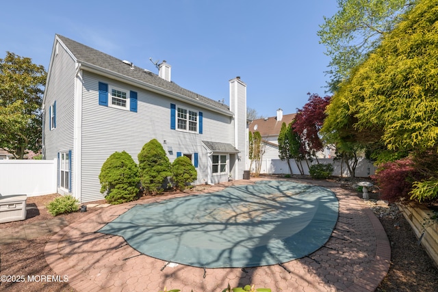 rear view of house with a fenced in pool, a chimney, and a fenced backyard