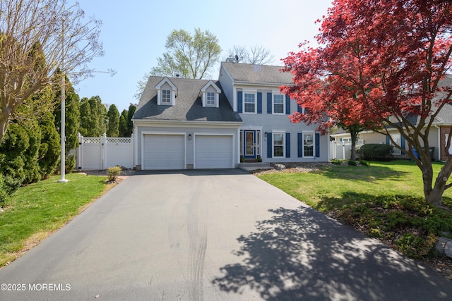 colonial inspired home with fence, a front lawn, aphalt driveway, and an attached garage