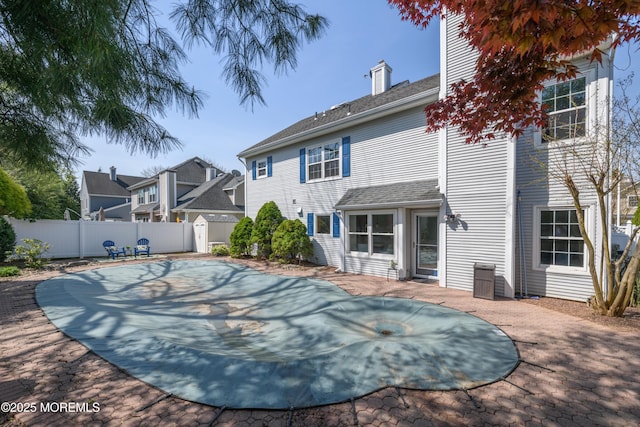 rear view of house with a chimney, fence, a residential view, and a patio area