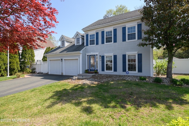 colonial inspired home with fence, a front yard, aphalt driveway, and a garage