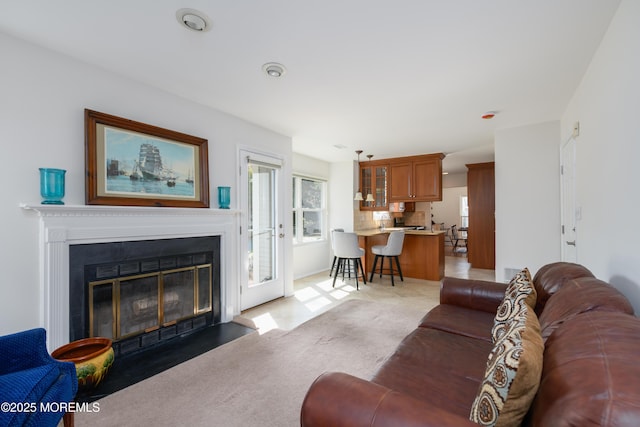 living area with a fireplace with flush hearth and light colored carpet