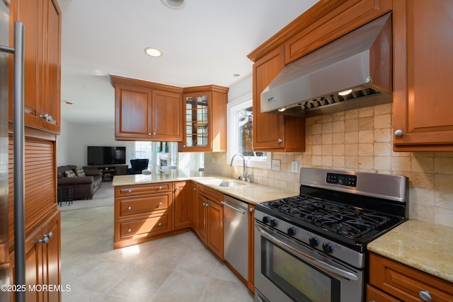 kitchen with brown cabinets, a sink, ventilation hood, and appliances with stainless steel finishes