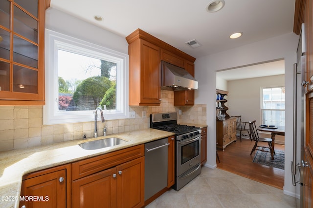 kitchen featuring stainless steel appliances, a healthy amount of sunlight, under cabinet range hood, and a sink
