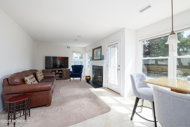 living area featuring visible vents and a fireplace with flush hearth