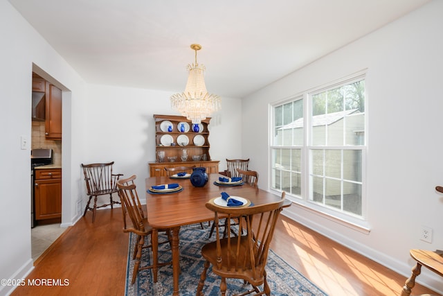dining area featuring baseboards, a notable chandelier, and light wood finished floors