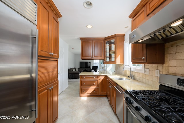 kitchen featuring appliances with stainless steel finishes, a sink, backsplash, and under cabinet range hood