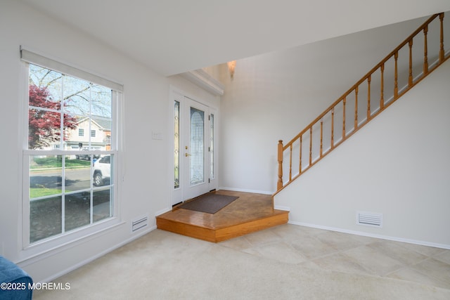 foyer with carpet flooring, visible vents, stairway, and baseboards