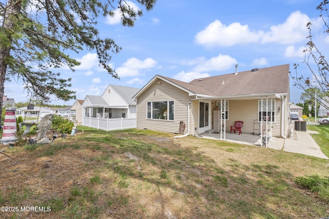 back of house featuring a lawn, roof with shingles, a patio area, and fence