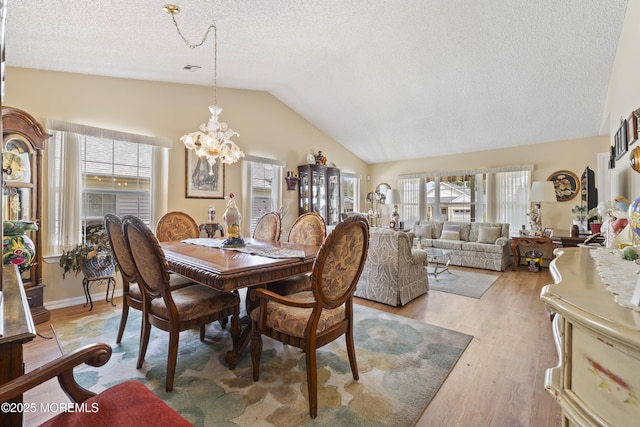 dining room with lofted ceiling, a textured ceiling, a chandelier, visible vents, and light wood-style floors