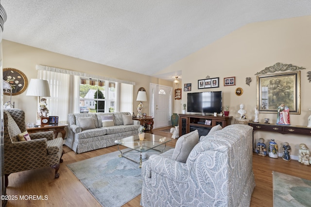 living area with a textured ceiling, vaulted ceiling, and wood finished floors