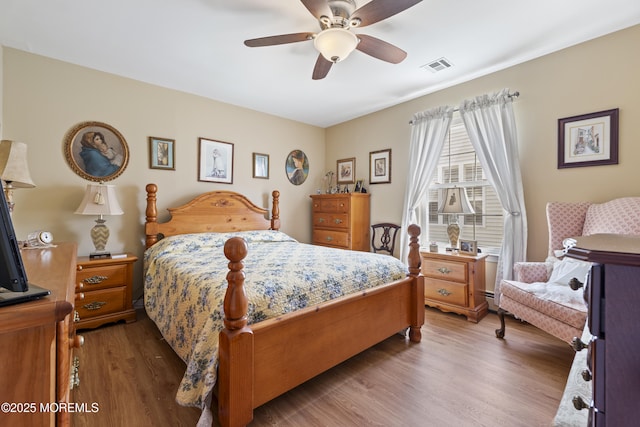 bedroom featuring a ceiling fan, visible vents, and wood finished floors