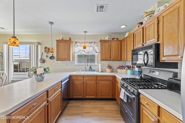 kitchen featuring a sink, appliances with stainless steel finishes, visible vents, light countertops, and light wood-type flooring