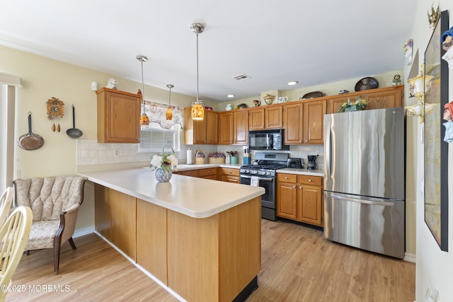 kitchen featuring a peninsula, appliances with stainless steel finishes, decorative backsplash, and visible vents