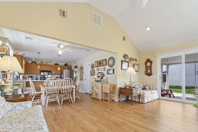 living room with light wood finished floors, ceiling fan, high vaulted ceiling, and visible vents