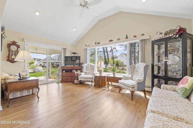 living area featuring wood finished floors, a healthy amount of sunlight, a ceiling fan, and baseboard heating