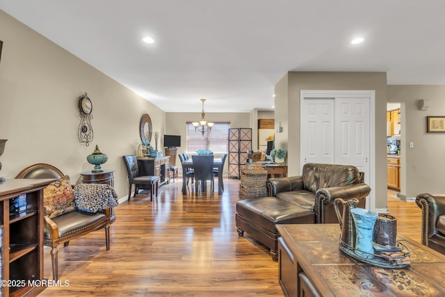 living room with light wood-style floors, baseboards, recessed lighting, and a notable chandelier