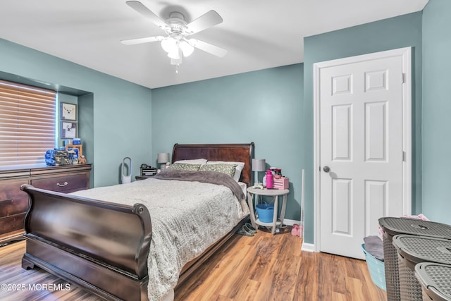bedroom with a ceiling fan, baseboards, and wood finished floors
