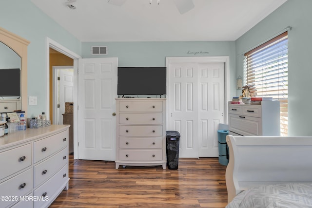 bedroom with a ceiling fan, visible vents, dark wood-style floors, and a closet