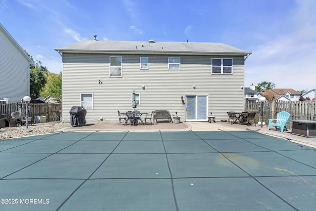 rear view of house with fence, a fenced in pool, outdoor dining space, and a patio area
