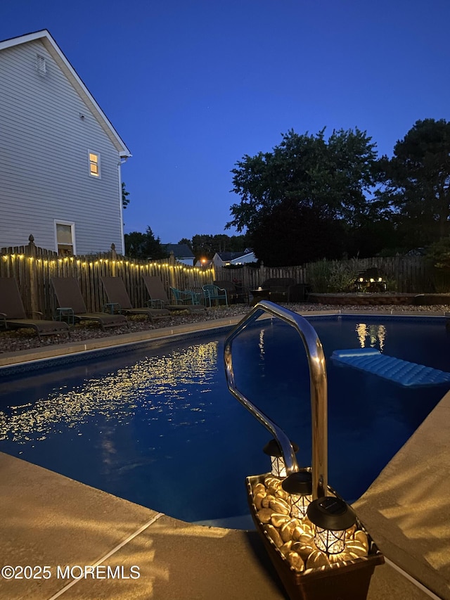 pool at twilight featuring a fenced in pool and a fenced backyard