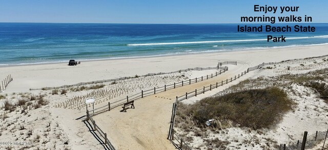 view of water feature featuring fence and a beach view