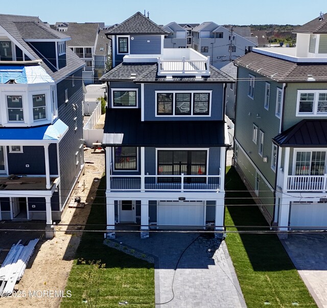 view of front of home featuring a balcony, decorative driveway, a shingled roof, an attached garage, and a residential view