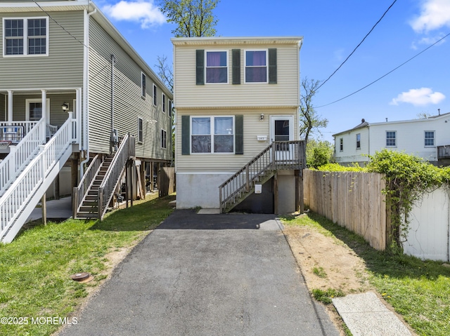 view of front facade featuring stairway, fence, and a front yard