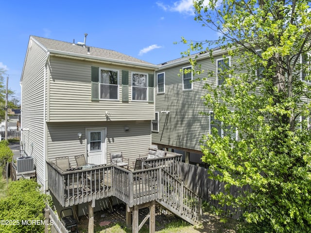 rear view of property featuring a wooden deck, central AC, and fence
