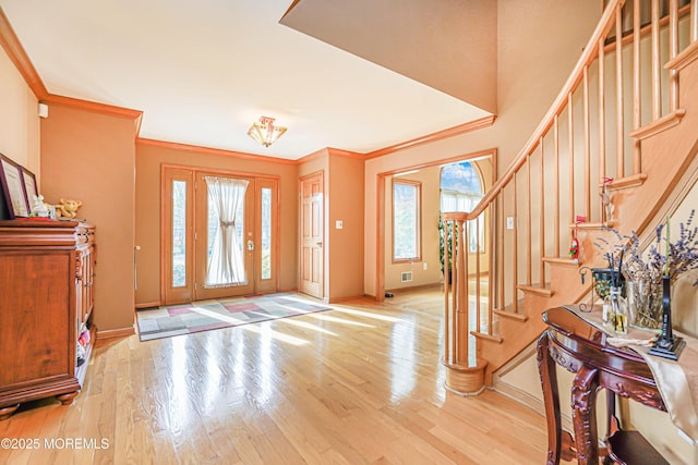 entryway with crown molding, baseboards, wood finished floors, visible vents, and stairway