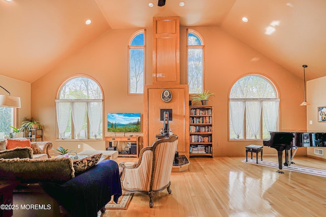 living area featuring high vaulted ceiling, visible vents, and wood finished floors