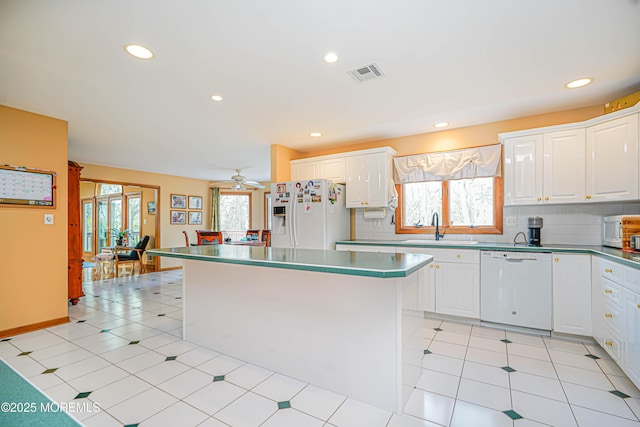 kitchen featuring a sink, plenty of natural light, white appliances, and visible vents