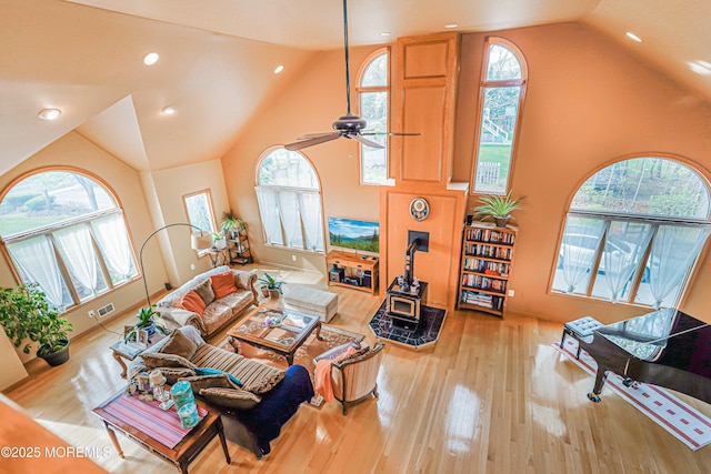 living area with visible vents, wood-type flooring, a wood stove, and a wealth of natural light