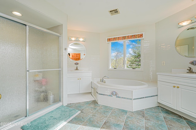 bathroom featuring visible vents, two vanities, a bath, and a stall shower