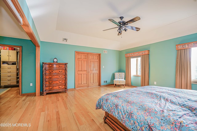 bedroom featuring baseboards, a closet, wood finished floors, and visible vents