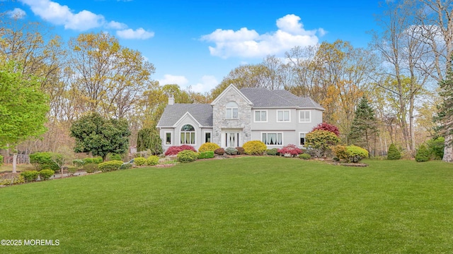 view of front of property with a front yard, stone siding, and a chimney