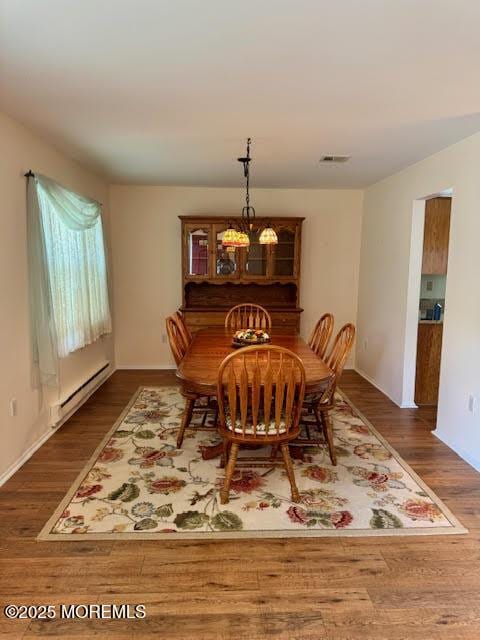 dining room with a baseboard radiator, wood finished floors, visible vents, and baseboards