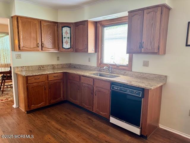 kitchen featuring dark wood-style floors, a sink, brown cabinetry, crown molding, and dishwasher