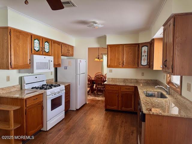 kitchen featuring visible vents, white appliances, brown cabinetry, and a sink