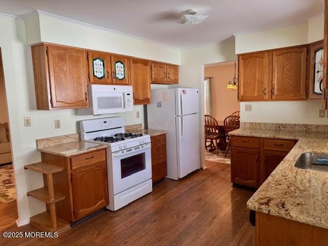 kitchen with brown cabinetry, white appliances, dark wood-style flooring, and crown molding