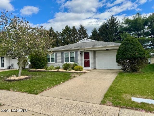 single story home featuring a front yard, concrete driveway, and an attached garage
