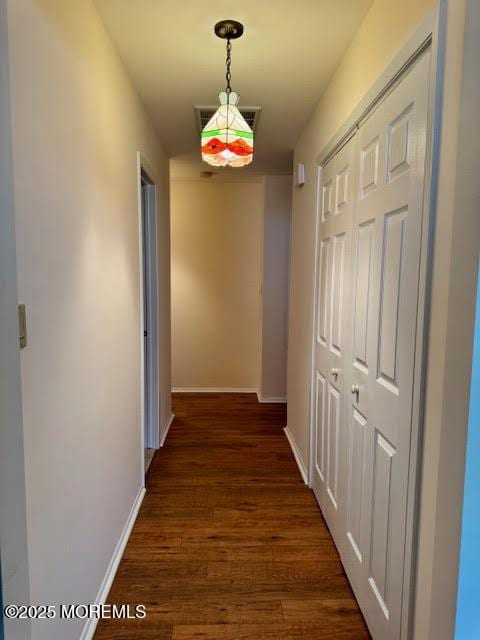 corridor featuring visible vents, baseboards, and dark wood-type flooring
