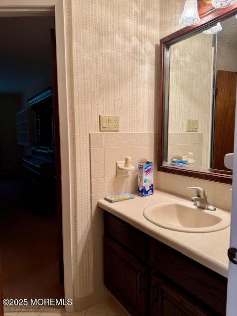 bathroom with vanity and wallpapered walls