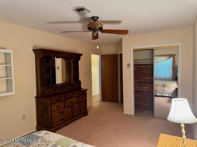 carpeted bedroom with a closet, visible vents, and a ceiling fan