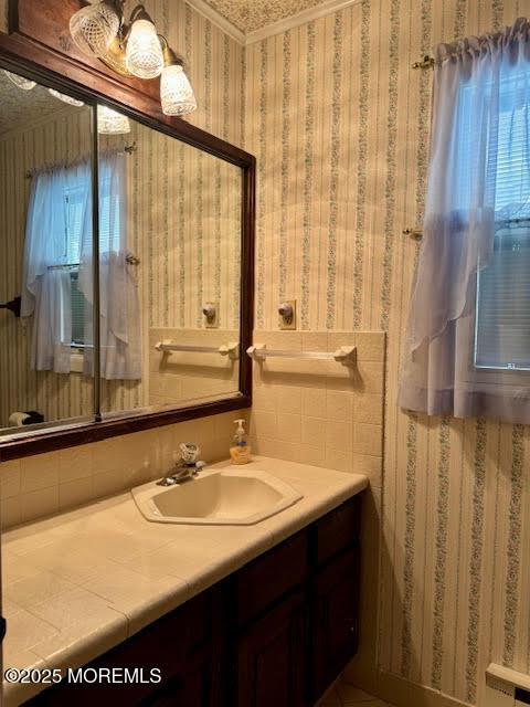 bathroom with vanity and wallpapered walls